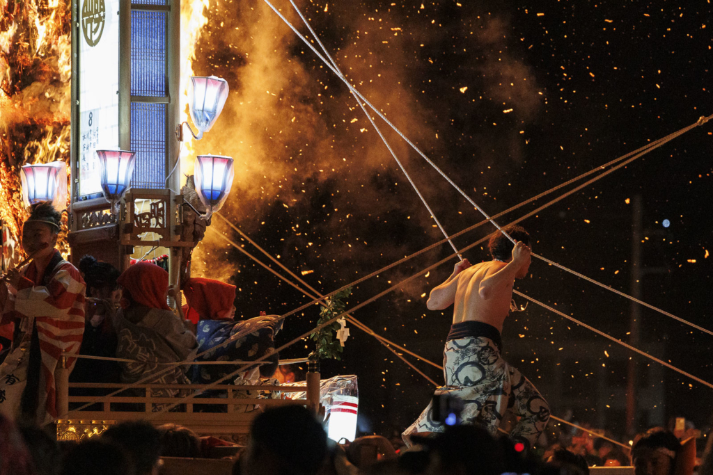 Boy standing on Kiriko lanern with fire on the background