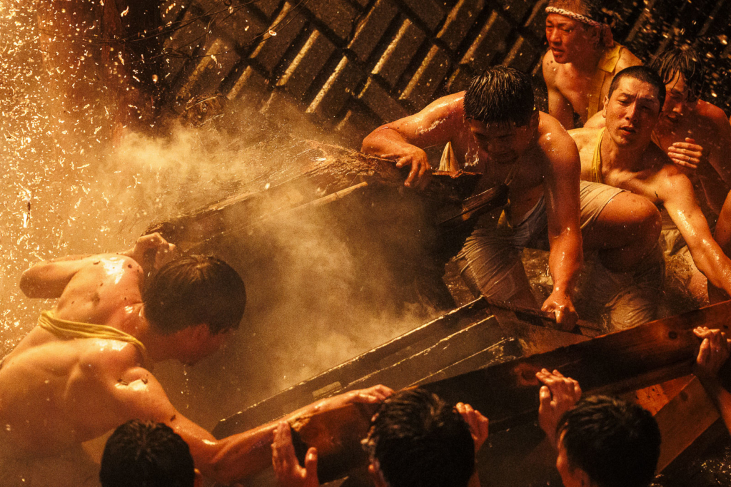 Men in the river crash the mikoshi with embers falling from above